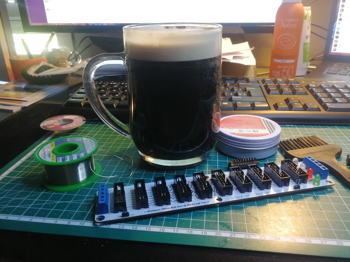An electronics busboard being assembled beside a dark drink