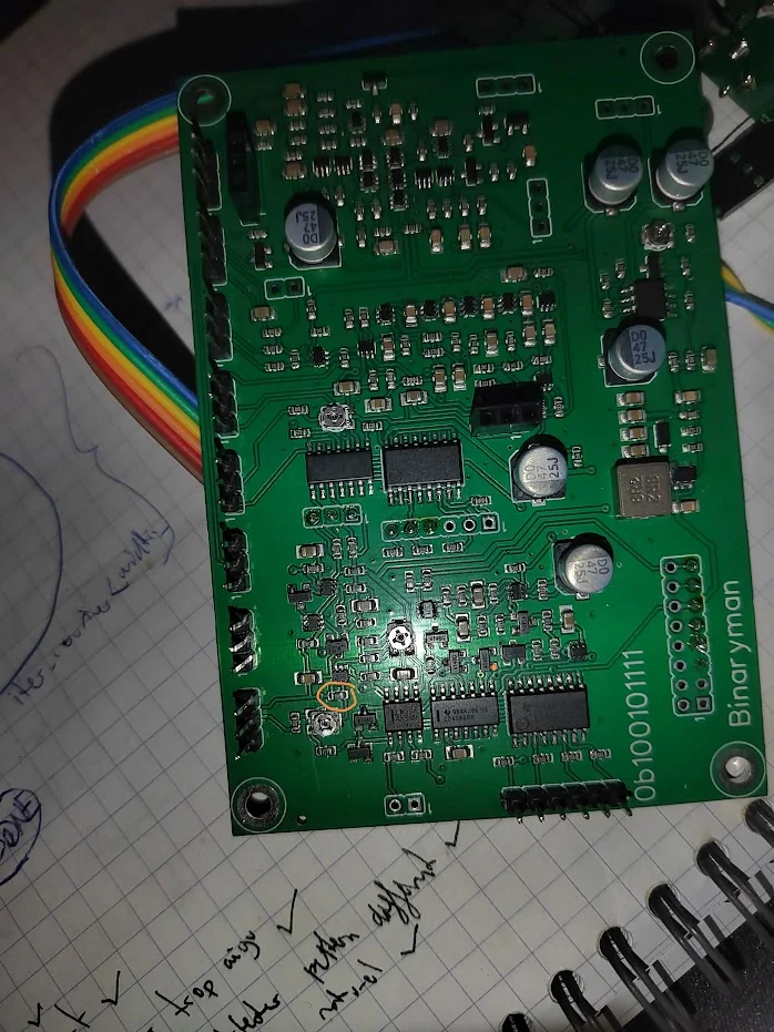 Close-up of the green Binaryman x0x board on a notebook, with a small component area circled in yellow near the lower left.