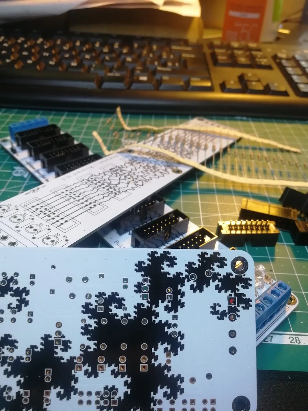 Bus boards with shrouded power headers and screw terminals, beside a PCB with fractal silkscreen artwork.