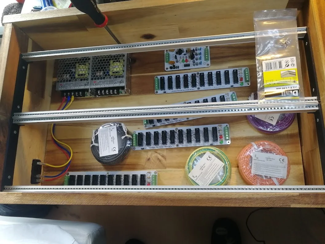 The acacia case with rails installed, populated bus boards, two power supplies, and coils of coloured wire laid out inside.
