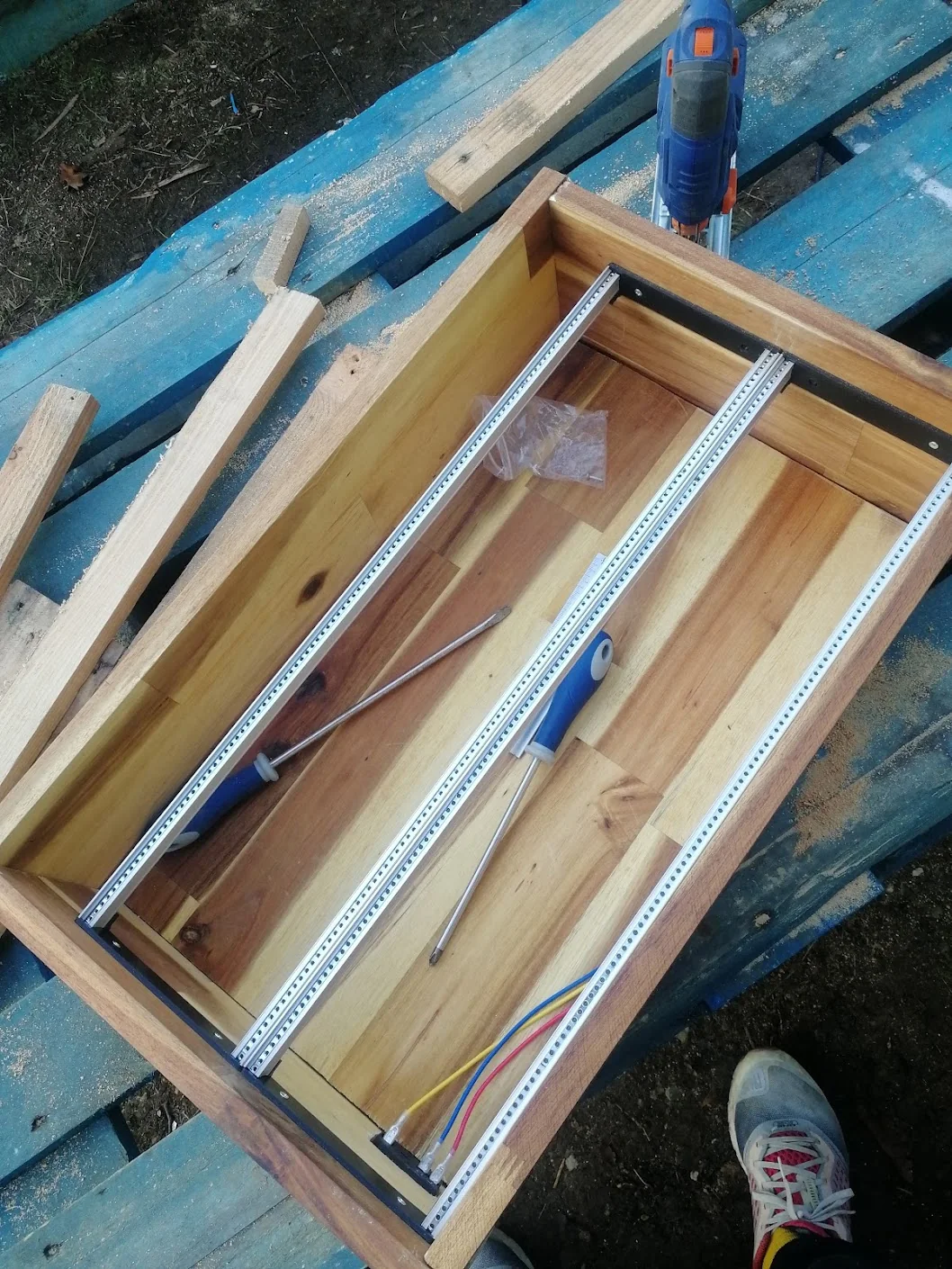Aluminium Eurorack rails fitted to black side brackets inside the acacia case on an outdoor workbench.