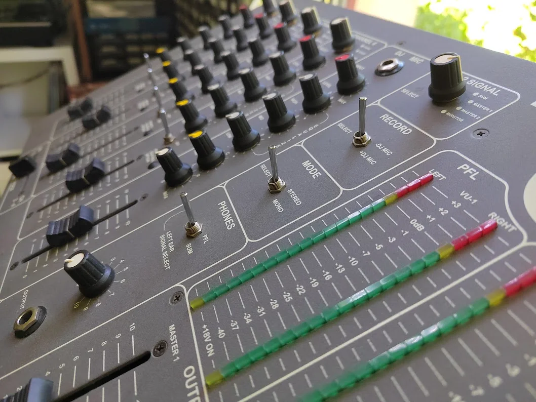 Close-up of the mixer's PFL and output LED meters, monitoring switches, and master controls.